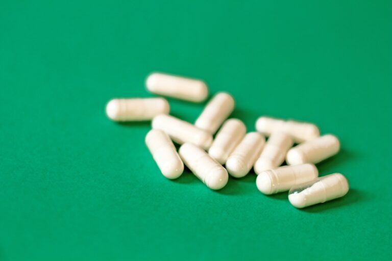 A pile of white pills sitting on top of a green table